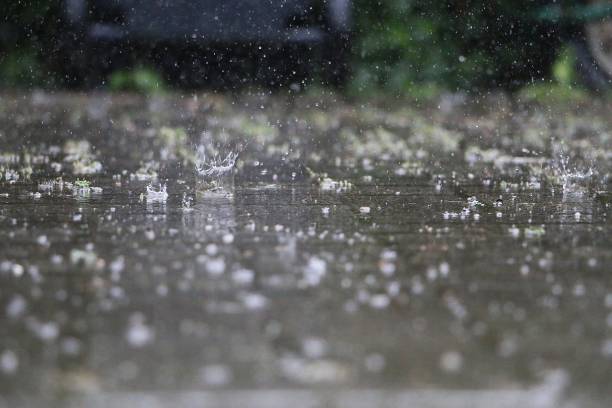 close up of falling and splashing rain on the street stock photo
