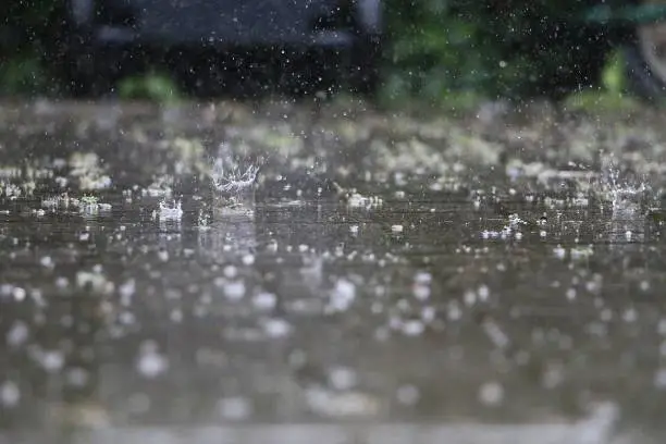 Photo of close up of falling and splashing rain on the street