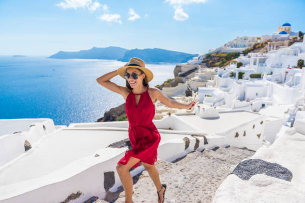 Travel Tourist Happy Woman Running Stairs Santorini Travel Tourist Happy Woman Running Stairs Santorini, Greek Islands, Greece, Europe. Girl on summer vacation visiting famous tourist destination having fun smiling in Oia. woman in red dress stock pictures, royalty-free photos & images