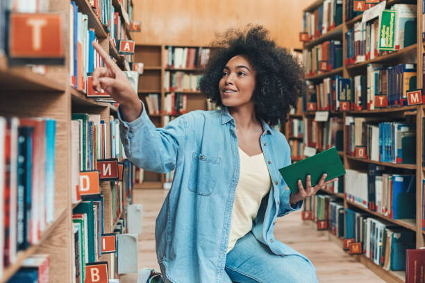 図書館の若い女性 - bookshelf book reference book choosing ストックフォトと画像