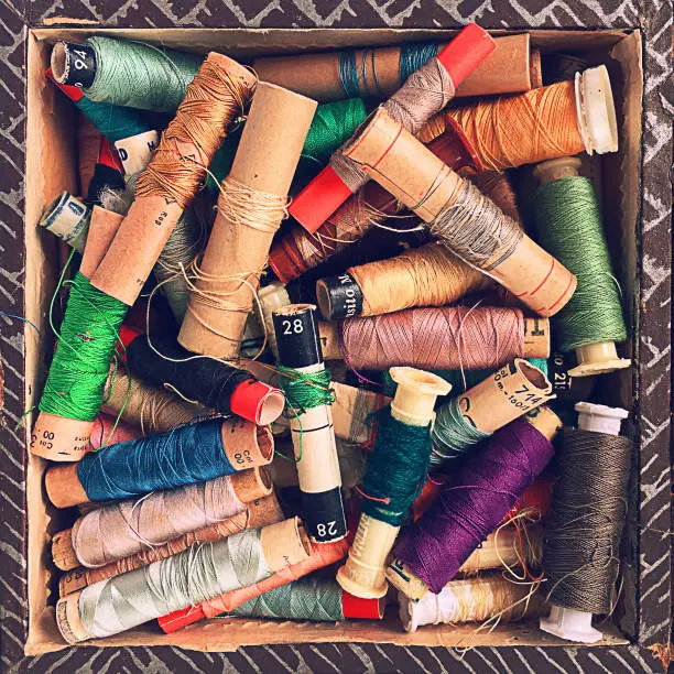 Squared frame photo of Vintage thread spools in a box from above.