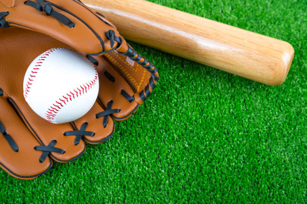 istock baseball time, glove, ball and bat on green grass 1161976328
