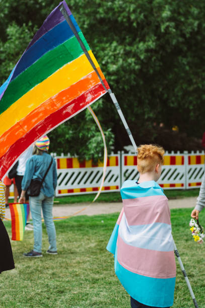 garçon avec l'arc-en-ciel et le drapeau transgenre sur le festival de fierté d'helsinki dans le parc public de kaivopuisto - editorial vertical homosexual people photos et images de collection
