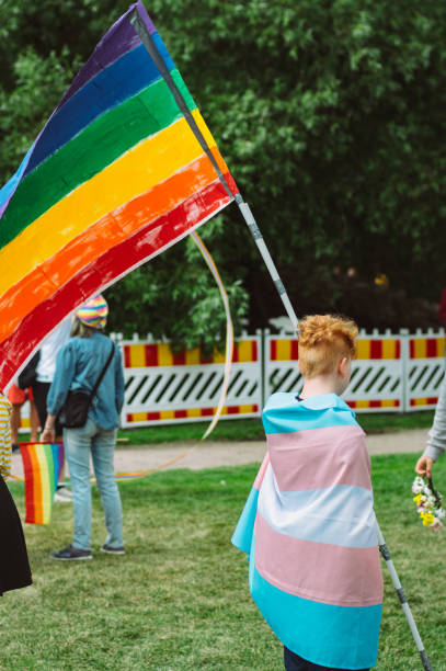 мальчик с радугой и трансгендерным флагом на фестивале helsinki pride в общественном парке кайвопуисто - editorial vertical homosexual people стоковые фото и изображения