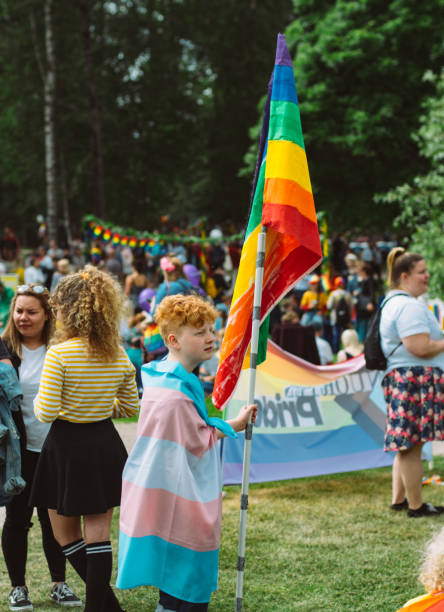 boy with rainbow and transgender flag on helsinki pride festival in kaivopuisto public park - editorial vertical homosexual people imagens e fotografias de stock