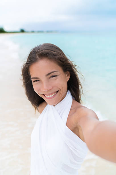 selfie von schönen asiatischen gemischten rasse frau am strand trägt weiße vertuschung - women sarong beach white stock-fotos und bilder