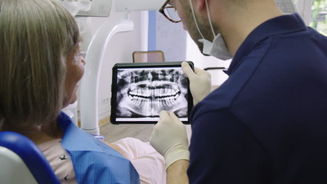 Patient and dentist discussing over medical x-ray