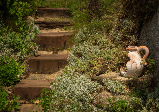 Old broken ceramic candlestick beside the rustic wooden steps in the summer garden.