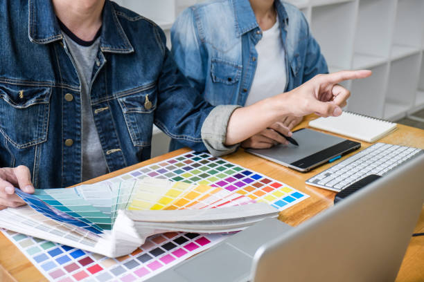istock Two colleagues creative graphic designer working on color selection and drawing on graphics tablet at workplace, Color swatch samples chart for selection coloring 1161989347