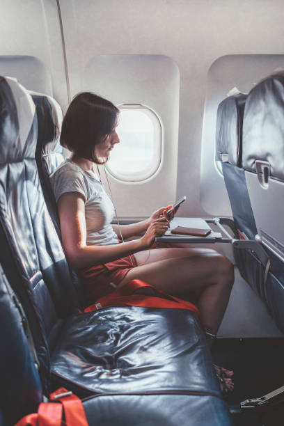 istock Young woman on a plane with a smartphone in her hands 1161989593