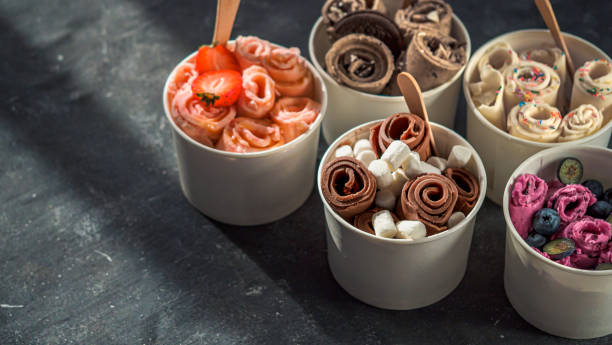 rolled ice creams in cone cups on dark background stock photo