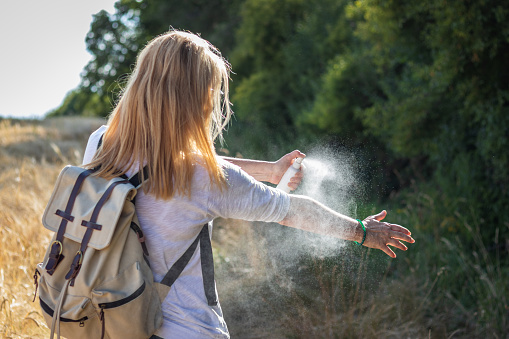 Mujer turista aplicando repelente de mosquitos en la mano durante la caminata en la naturaleza. Repelente. photo