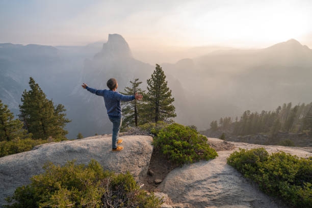 Young man cstamding arms outstretched on top of Yosemite valley, USA at sunrise Young man cstamding arms outstretched on top of Yosemite valley, USA at sunrise mariposa county stock pictures, royalty-free photos & images