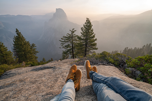 Personal perspective of couple relaxing on top of Yosemite valley; feet view; 
People travel vacations relaxation concept