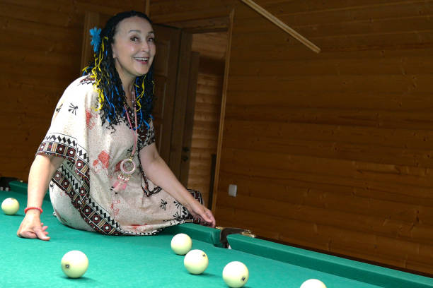 istock Senior woman relax and fun sits on the pool table and rejoice. Selective focus. 1161995598