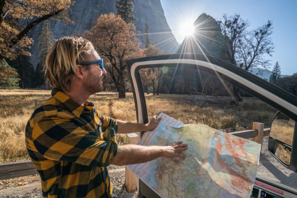 istock Road trip concept; man driving in USA checking at road map for directions 1161996548