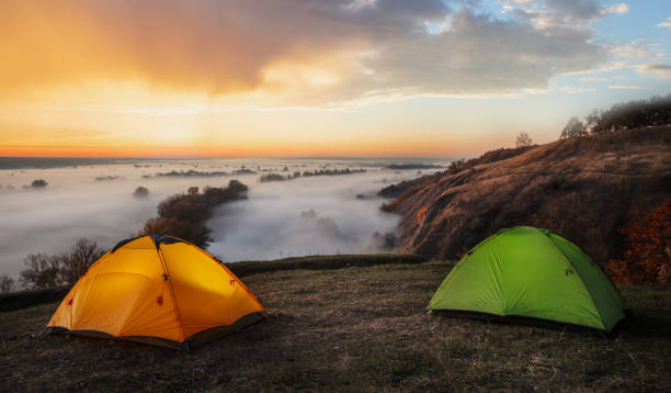 istock Orange and green tents over river sheltered by mist 1161996854
