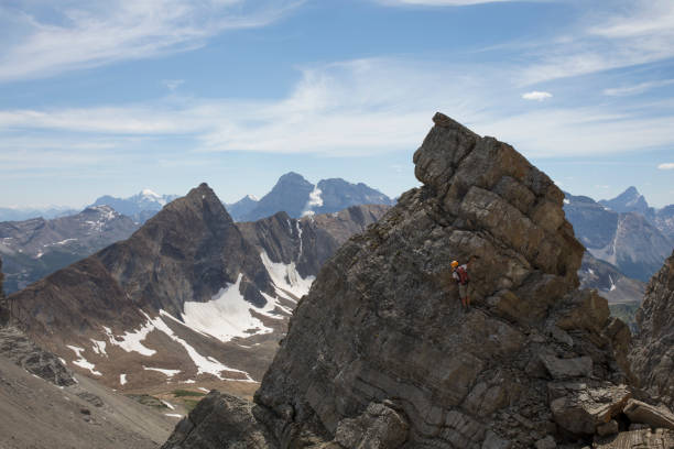 mountaineer scrambles up pinnacle in mountains - conquering adversity wilderness area aspirations achievement imagens e fotografias de stock