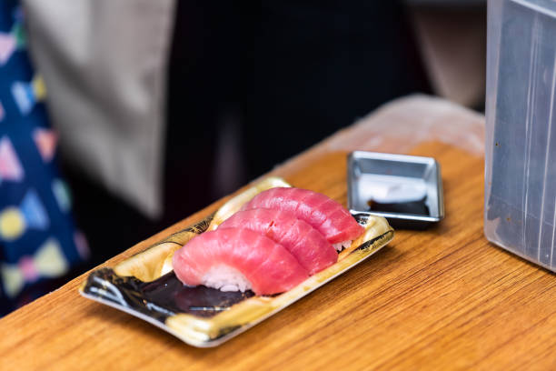 plan rapproché de trois sushis de sashimi de riz de thon avec l'assiette de sauce de soja sur la table en bois dans le marché extérieur de poissons de tsukiji de ginza, japon de tokyo - 11084 photos et images de collection