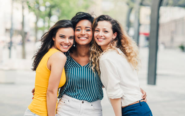 Girls hanging out together Portrait of a three beautiful young women smiling and looking at camera. cheek to cheek photos stock pictures, royalty-free photos & images