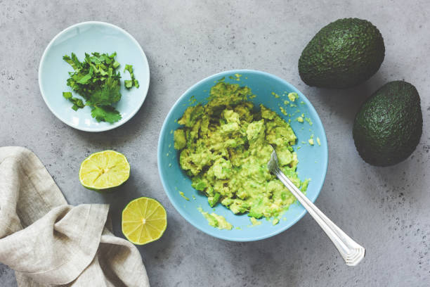 Mashed avocado guacamole sauce in bowl Mashed avocado guacamole sauce in blue ceramic bowl on grey concrete background. Table top view. Healthy vegan vegetarian food, spread for bread or toast or sauce for salad guacamole stock pictures, royalty-free photos & images