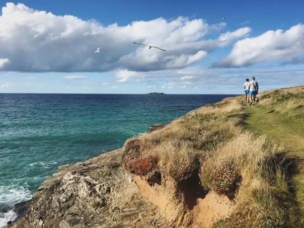 Photo of Father and son walking dog at the coast path in Harlyn Bay, north coast of Cornwall, England