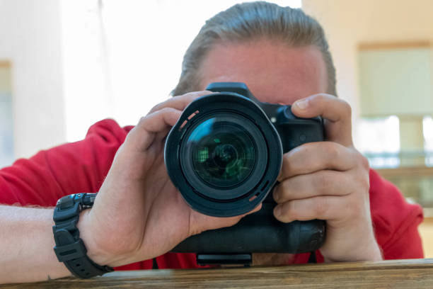 istock Young man is taking a selfie photo through the mirror with focus on camera lens 1162011943