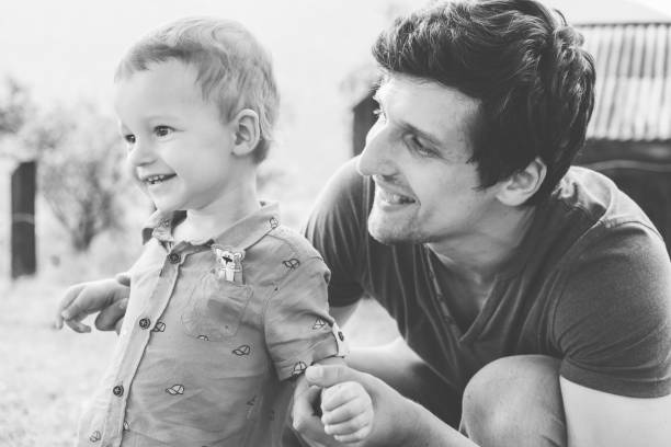 istock Happy young father and little son playing and having fun outdoors. Green mountains on background. Lifestyle. Black and white. 1162013197