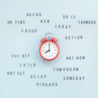 Creative top view flat lay of alarm clock with messages about delay or starting doing task copy space blue background minimal style. Concept of procrastination, time management in business and life