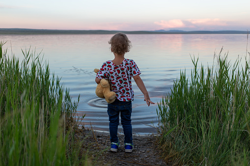 Little boy standing on shore of the lake
