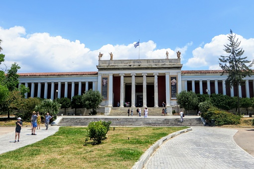 Athens, Greece - July 13th, 2019: Looking outside at the front of the world famous National Archaeological Museum in Athens, Greece.  Several visitors are walking towards the entrance.