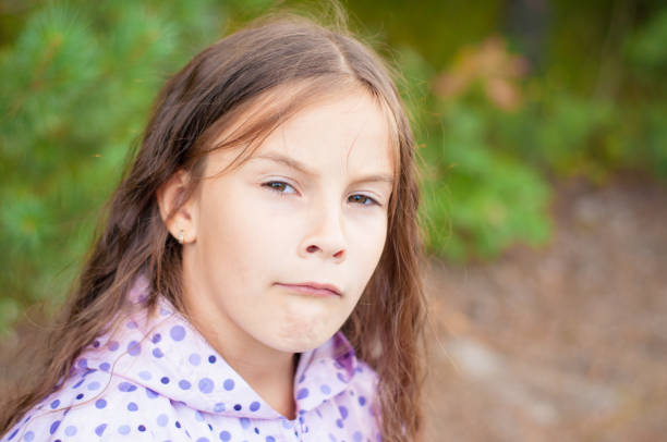 istock Sad little girl is looking with serious face at camera 1162019142