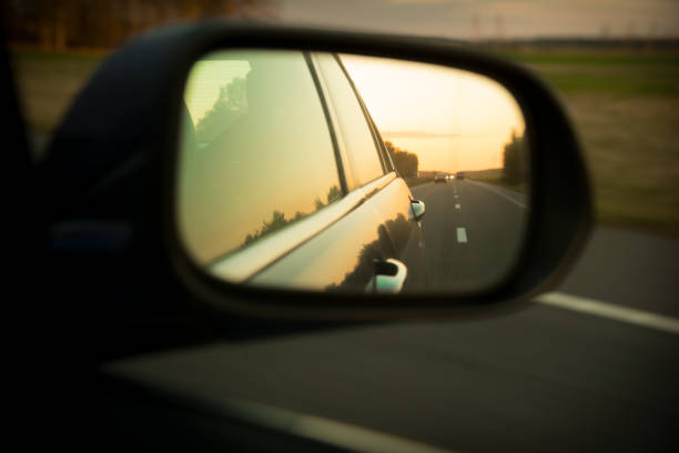 istock Dark road reflection with asphalt lines above the yellow sunset on side mirror rear view of moving car 1162019207