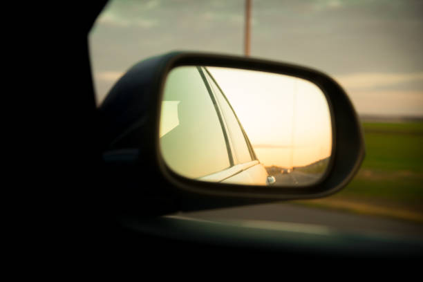 istock Road reflection with roadside lines above the sunset on side mirror rear view of moving car 1162019237