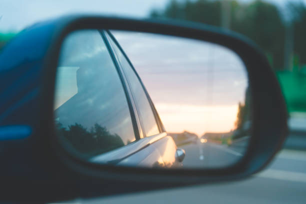 istock Straight road reflection above the sunset on side mirror rear view blue car 1162019265