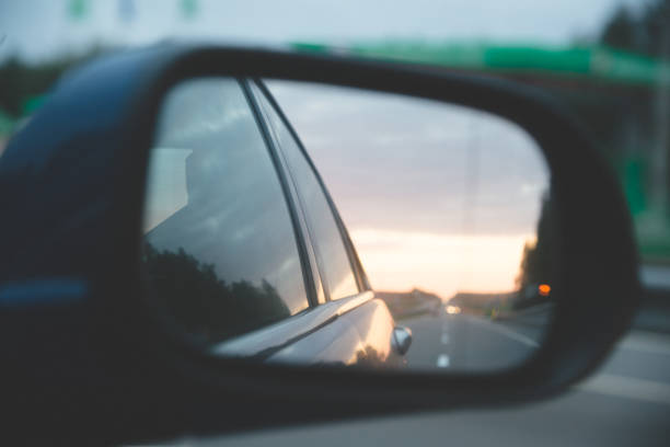 istock Road reflection above the sunset on side mirror rear view blue car 1162019305
