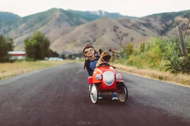 Photo of Boy and Dog in Toy Racing Car