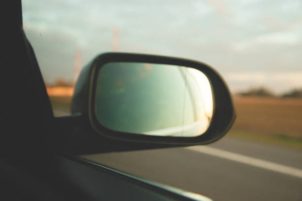 istock Side part of the road reflection above the sunset on side mirror rear view blue car 1162019447