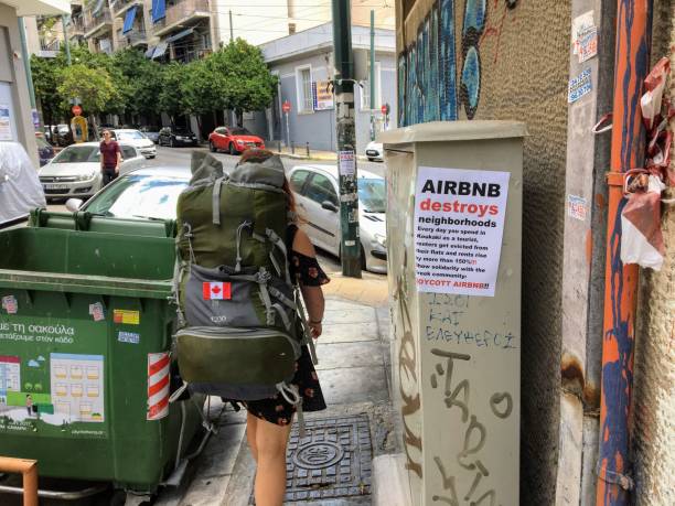 A tourist and Airbnb user walking past an anti-Airbnb posted in the Koukaki area of Athens, Greece. stock photo