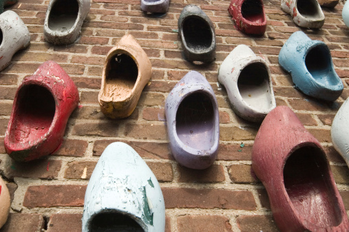 multicolored wooden shoes hanging on a brick wall