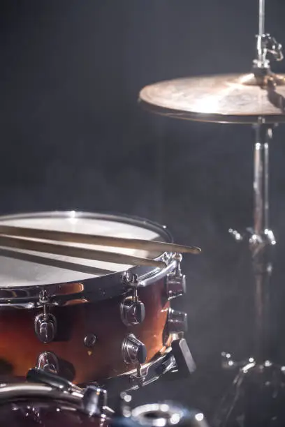 Photo of Close-up Drum set in a dark room against the backdrop of the spotlight. Atmospheric background symbol of playing rock or jazz drums.