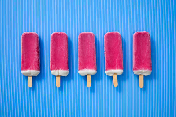 istock Red Ice cream Popsicles on a striped blue background 1162026548