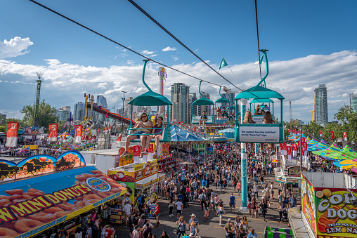 Calgary, Alberta - July 13, 2019: Ariel view of the Calgary Stampede grounds taken from a chairlift attraction on the Stampede grounds. The Calgary Stampede is one of the largest agricultural, rodeo and midways in the world. There are many festival goers visible on the ground.
