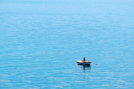 Pyrgi, Greece - May 30, 2019: Man in the middle of the sea, fishing on a rowing boat in Chios Island.