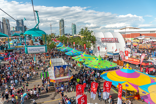 Calgary, Alberta - July 13, 2019: Ariel view of the Calgary Stampede grounds taken from a chairlift attraction on the Stampede grounds. The Calgary Stampede is one of the largest agricultural, rodeo and midways in the world. There are many festival goers visible on the ground.