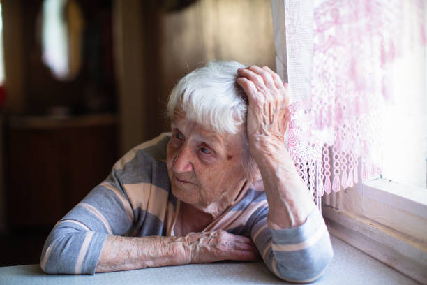 年配の女性は悲しそうに窓の近くに座っている。 - 16192 ストックフォトと画像