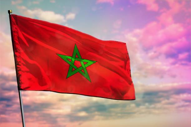 istock Fluttering Morocco flag on colorful cloudy sky background. Prosperity concept. 1162035547