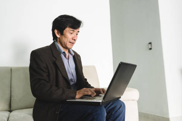 istock Japanese businessman sitting on sofa with laptop on leg 1162040801