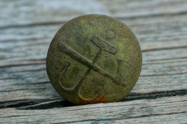 vecchio bottone in ottone con un emblema di un'ascia e un'ancora - brass buttons foto e immagini stock