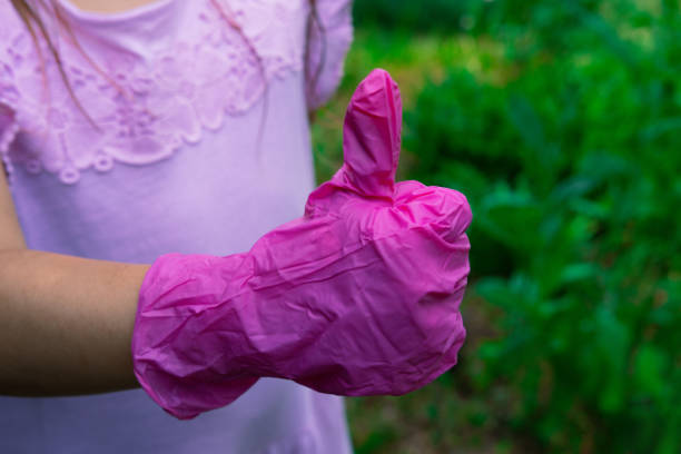 девушка в розовом платье показать розовый резиновый перчатку стороны, как - hand sign human hand ok sign grass стоковые фото и изображения